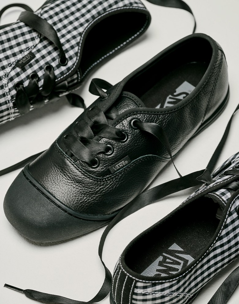 The black and white Checkerboard colorway and the black leather colorway of the Premium Authentic Prima on the floor of a photography studio.