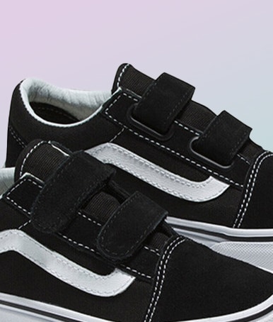 Close-up on a pair of black and white Old Skool V against a lavender and blue background.