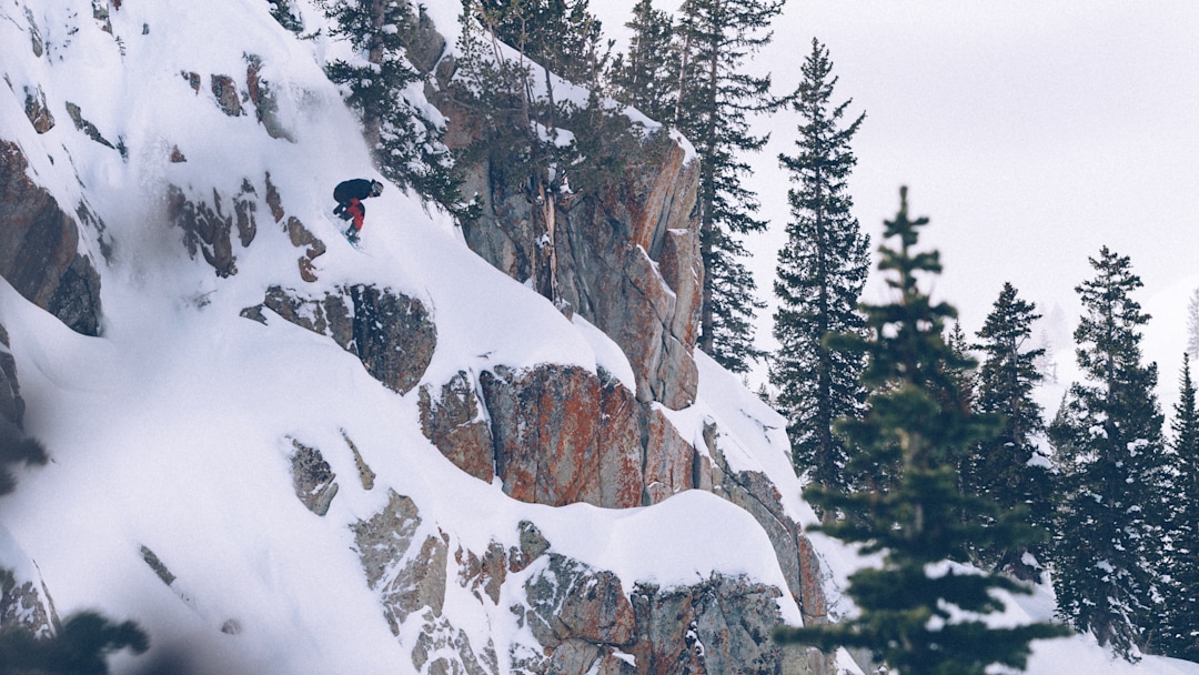 A snowboarder about to drop a cliff.