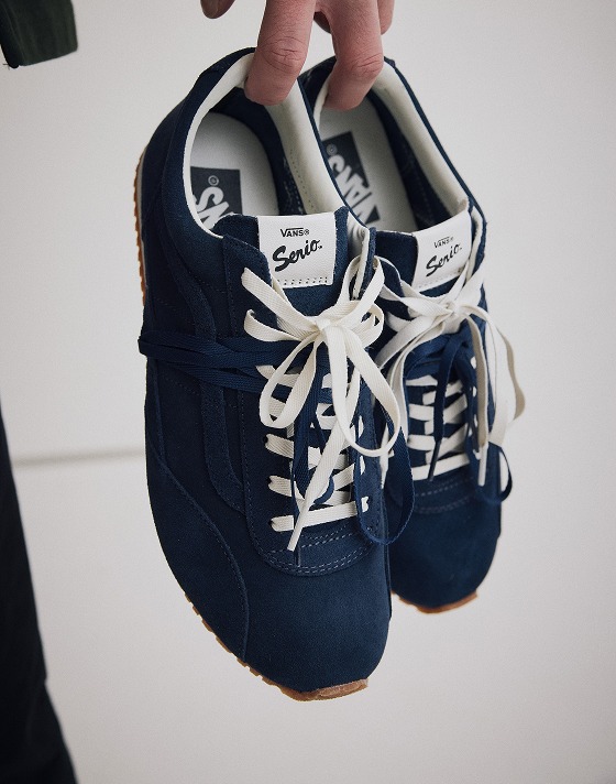 Someone holding a pair of navy and white Premium Super Lowpro Trainer.