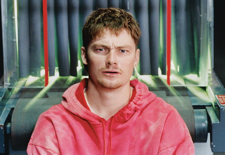 Professional skateboarder T-Funk staring into the camera incredulously with a TSA baggage scanner behind him.