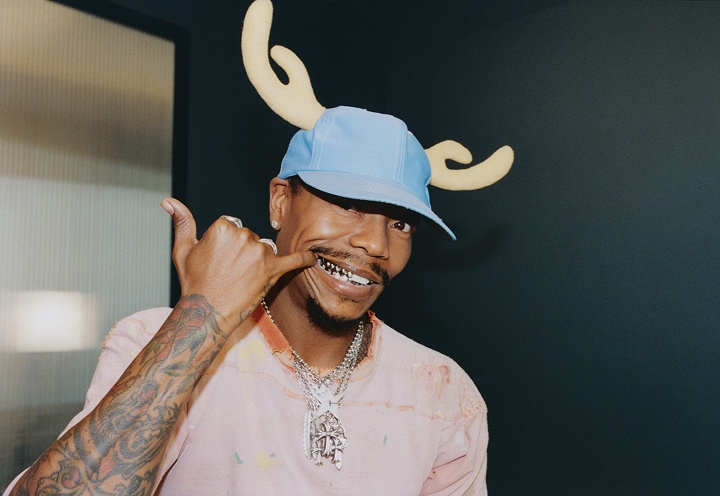 Turnstile bassist Franz Lyons looking into the camera and showing the silver grills on his teeth.