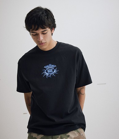 A young man poses in a photography studio wearing a dark blue Torched T-Shirt.