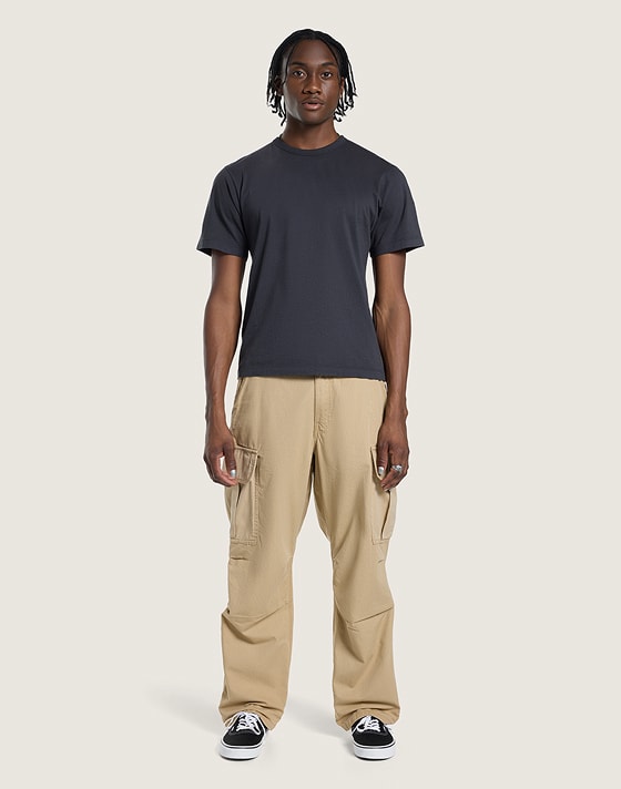 A young man poses in a photography studio wearing incense brown Range Relaxed Elastic Pants.