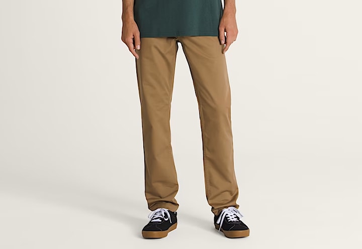 A knee-down shot of a young man wearing dirt brown Authentic Chino Slim Pants.