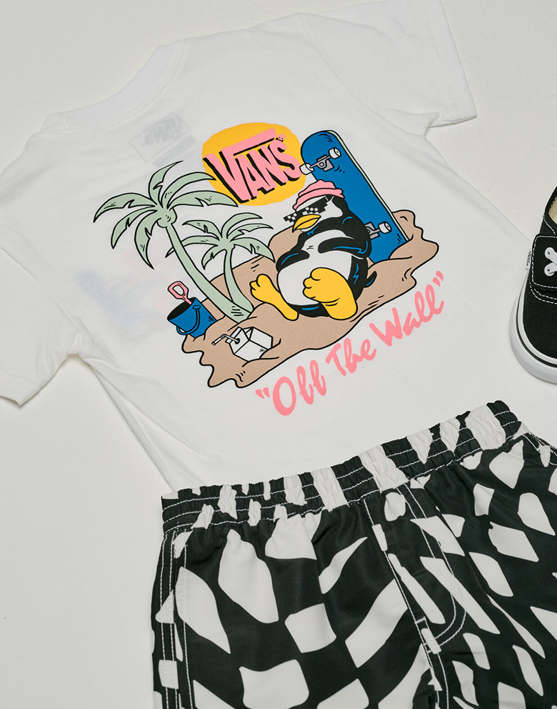 A Little Kids Yolo Penguin T-Shirt and Kids Primary II Printed Elastic Boardshorts on the floor of a photography studio.