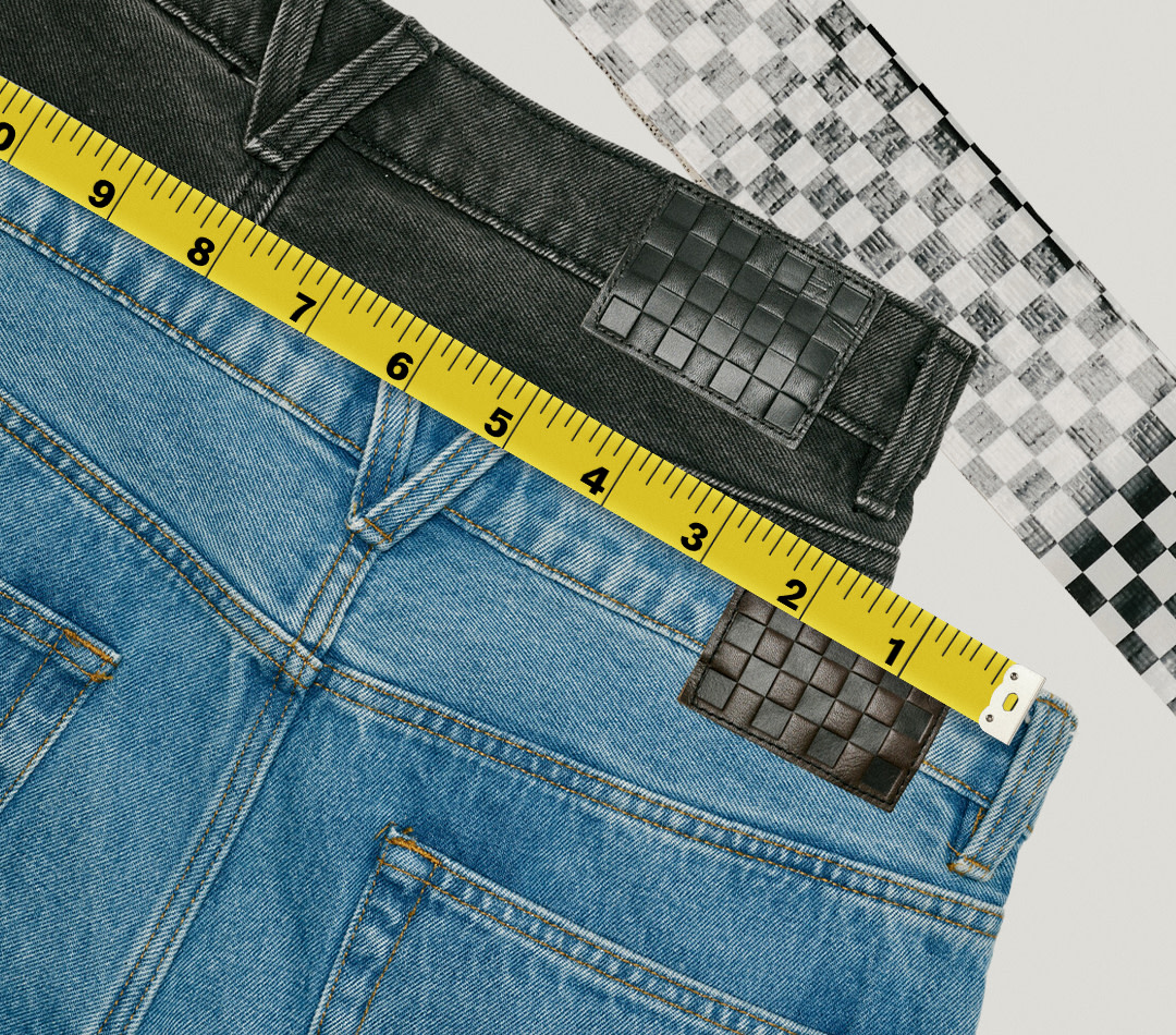 Two pairs of Check-5 Baggy Denim Pants stacked on top of each other with yellow measuring tape running across the waistlines.