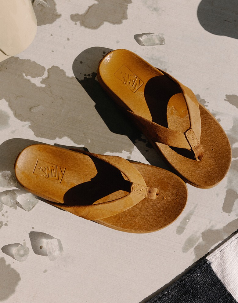 Top down view of two pairs of sandals sitting on the edge of a dock. On the left, the Mallorca Sandal in Brown, the right, Soft-Top Sandal in Brown.