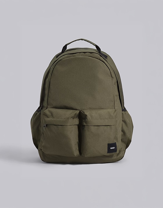 A mossy olive green Off The Wall Backpack on the floor of a photography studio.