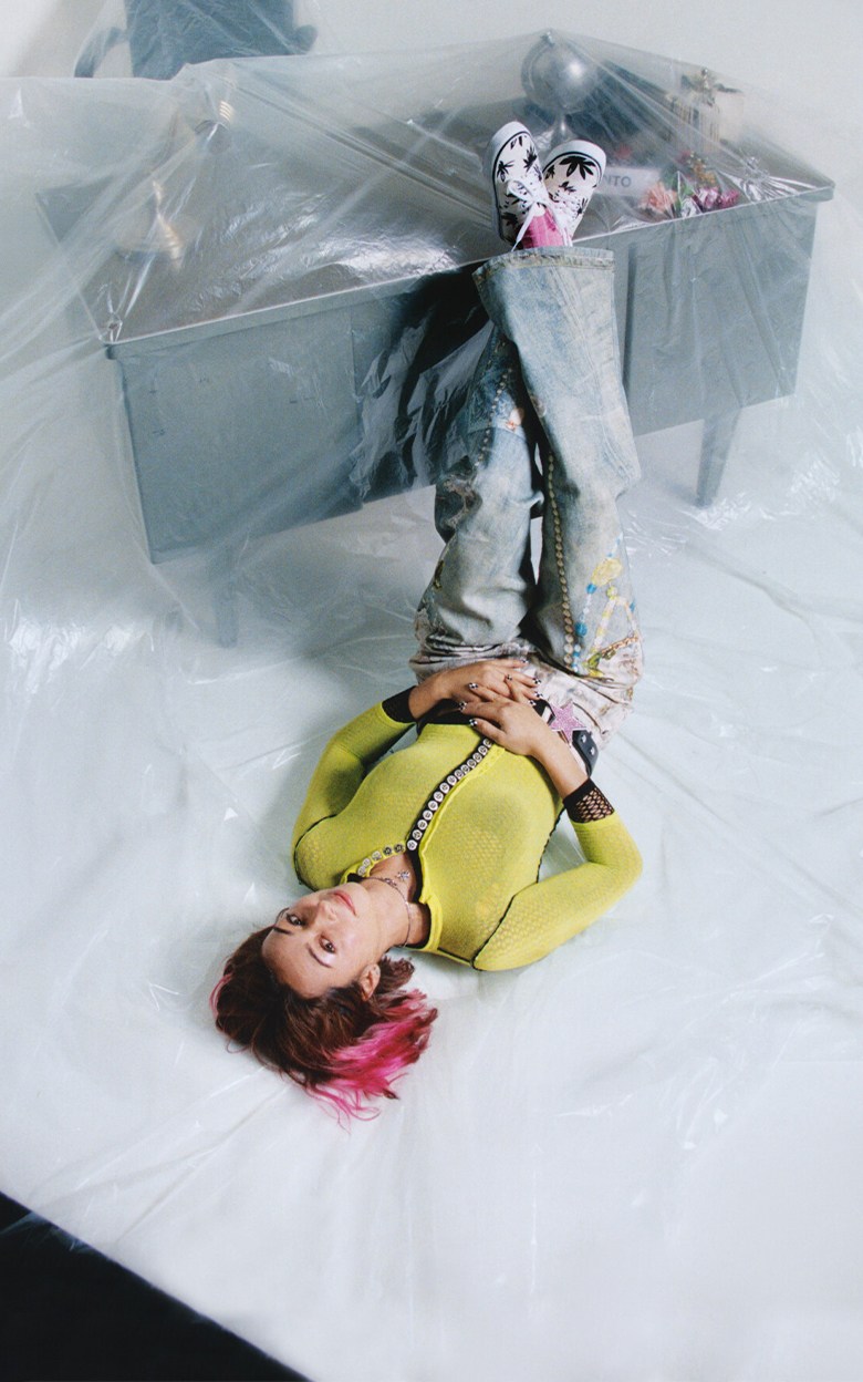 Vans Skate Team Rider Lizzie Armanto lying on an office floor with a desk covered in a plastic tarp wearing black and white palm print Authentic.