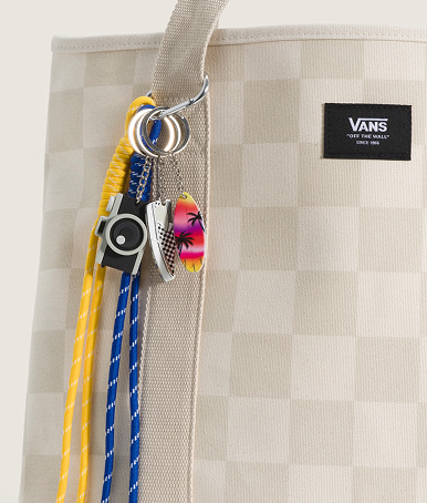 Close-up on a Vans Waffle Shop Sunset Snapshot Bag Charm Set hanging from an black and white Checkerboard Pergs Midi Tote Bag.