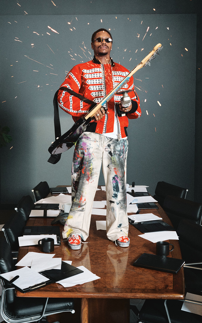 Turnstile Bassist Franz Lyons sitting on a conference room table wearing the red and white floral Premium Authentic from the Worn Loud collection.