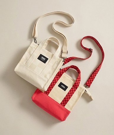 Deux sacs fourre-tout Lil Pergs, l’un couleur rouge cramoisi et l’autre couleur beige avoine, sur le sol d’un studio photo.