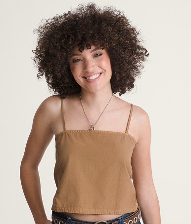 Une jeune femme porte une camisole courte brun teckel dans un studio photo.