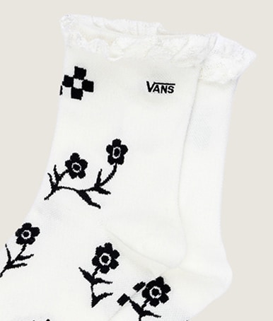 Plan rapproché du motif floral noir brodé sur une paire de chaussettes blanches Sereno à dentelle.