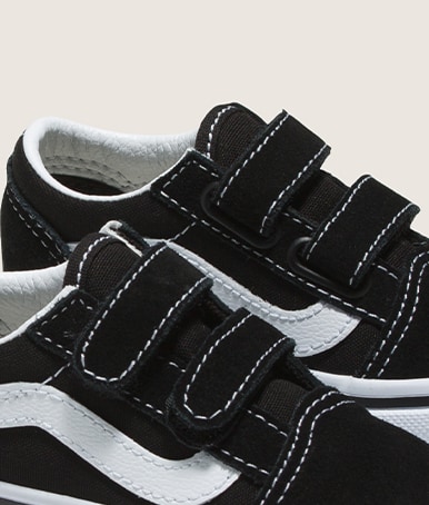 Close-up on the velcro flaps on a black and white Little Kids Old Skool V Shoe in a photography studio.