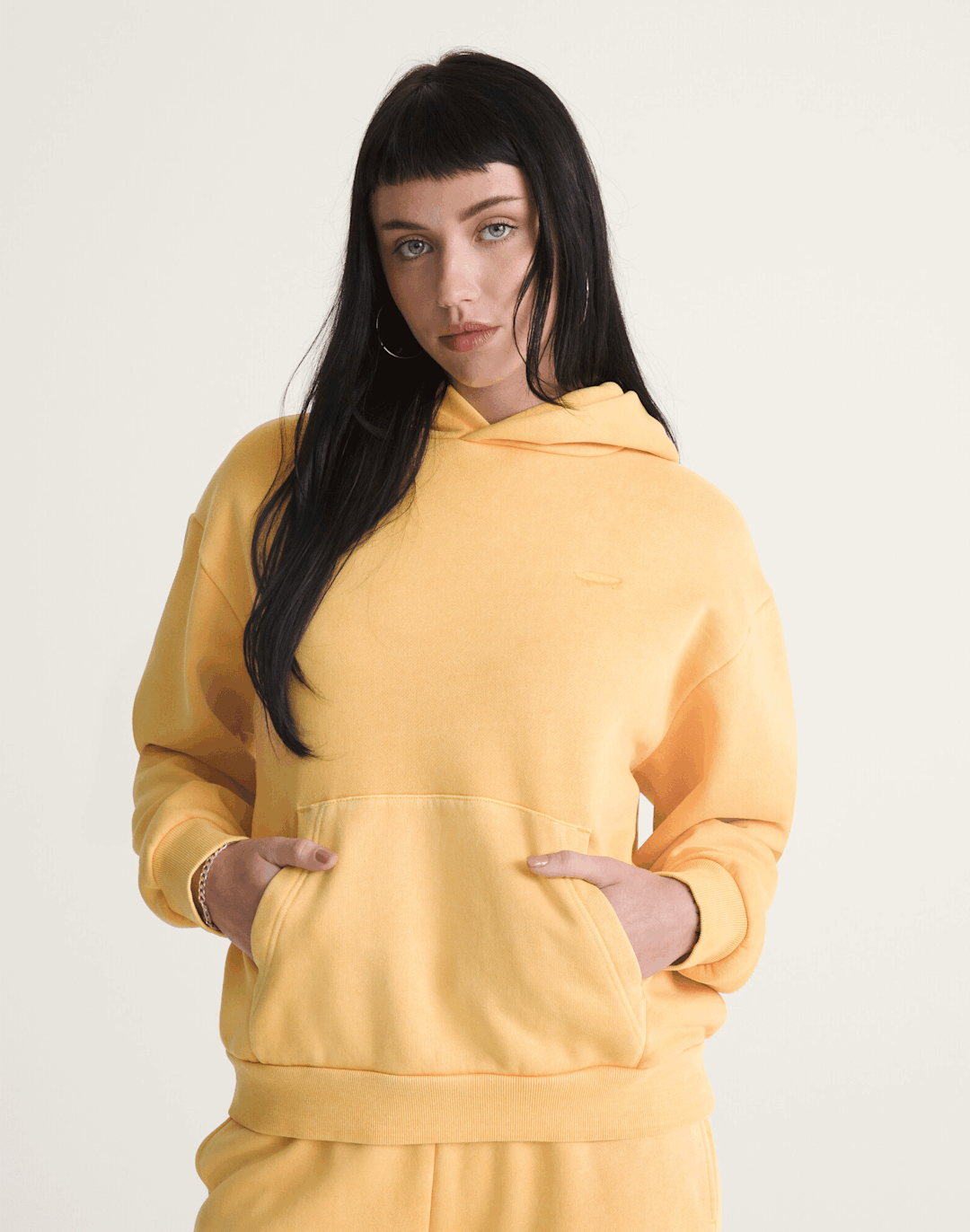 Une fille portant un ensemble assorti jaune, composé d’un chandail à capuchon et d’un pantalon de jogging.