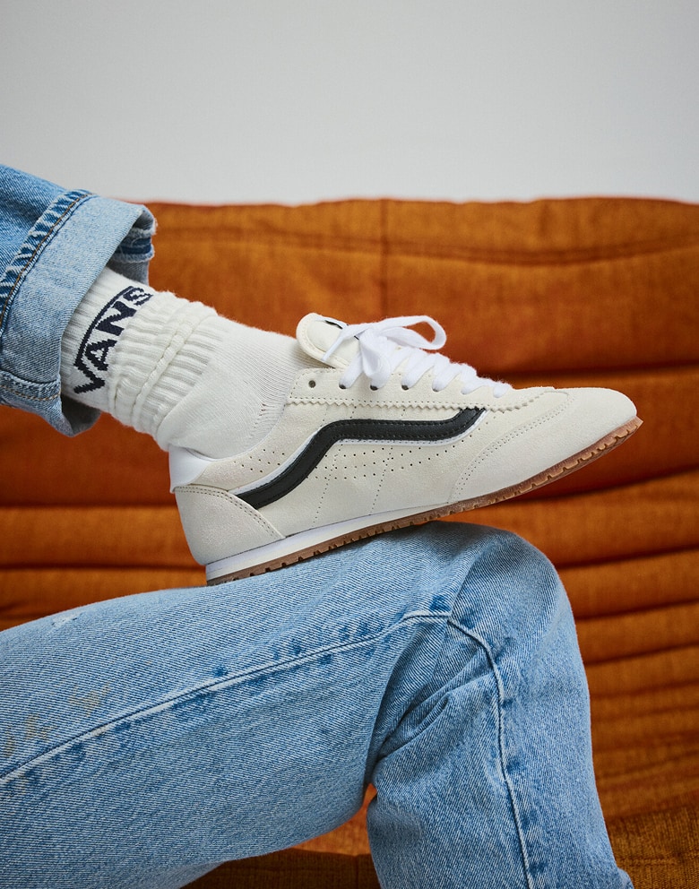 Close-up of someone wearing marshmallow white Super Lowpro with a black stripe paired with white Vans Classic Half Crew Socks.
