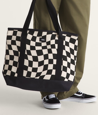 Close-up on someone holding a black and white Pergs Checkerboard Tote Bag in a photography studio.