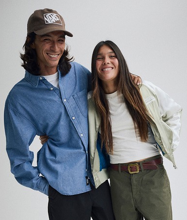 A young man and woman pose in a photography studio wearing Vans clothes and hats.