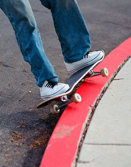 A knee-down shot of someone skating wearing white AVE Classic by Hockey and blue jeans.
