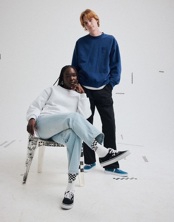 A young man and woman posing in a photography studio wearing black and blue Authentic shoes.