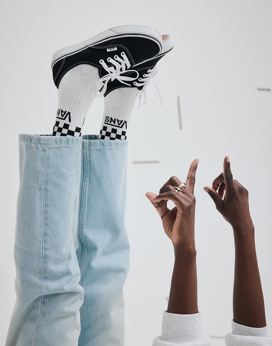A young man and woman posing in a photography studio wearing black and blue Authentic shoes.
