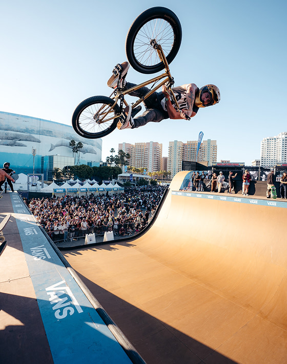 A BMX rider gets air on a halfpipe as the crowd watches at Vans Warped Tour.