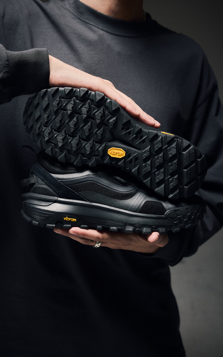 Close-up on someone showing the Vibram sole of a black Crosspath XC against a black pullover.