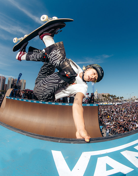 Vans Skate Team Rider Lizzie Armanto grabs the lip of a halfpipe as the crowd watches at Vans Warped Tour.
