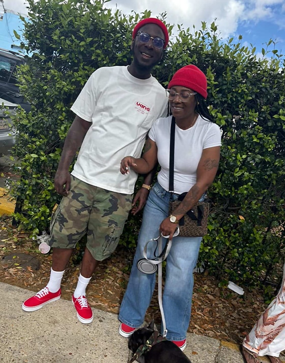 A young man and woman posing outside together wearing matching red Authentic.