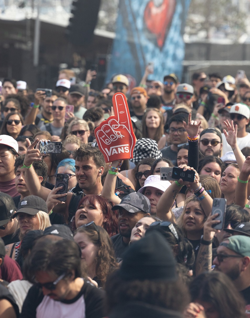 Close-up of someone holding a red Vans foam finger in a crowd at Vans Warped Tour.