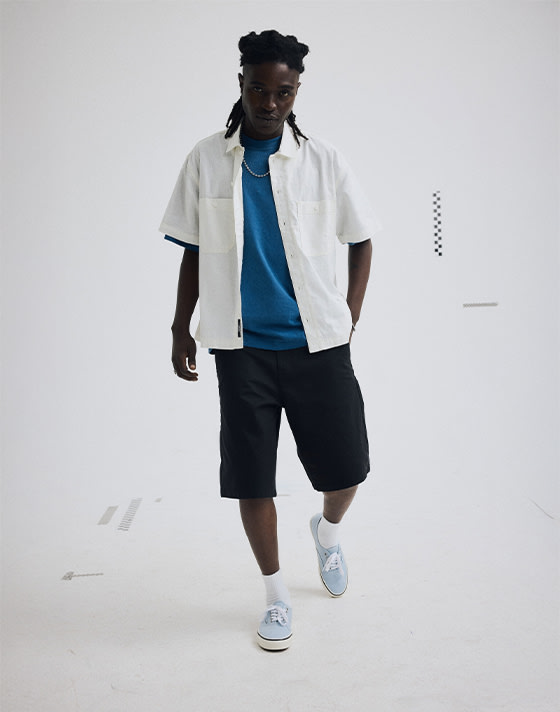 Head to toe look of a man wearing a white button up, a blue under shirt, black Authentic Chino Loose Shorts and the Soft Slate Blue Authentic shoes.