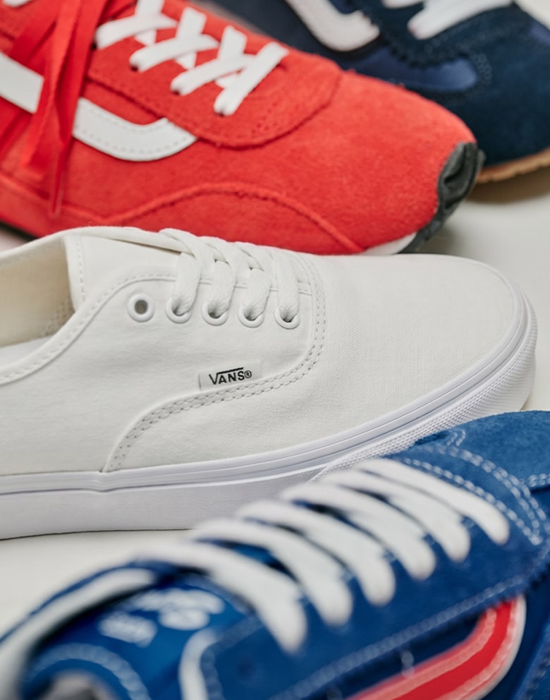 Close up shot of the Premium Super Lowpro Trainer in Tomato, the Authentic in True White and the Super Lowpro in blue arranged in a half circle.