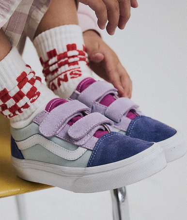 Close-up on a young girl wearing blue and purple Little Kids Old Skool V shoes with red Kids Classic Check Crew Socks.