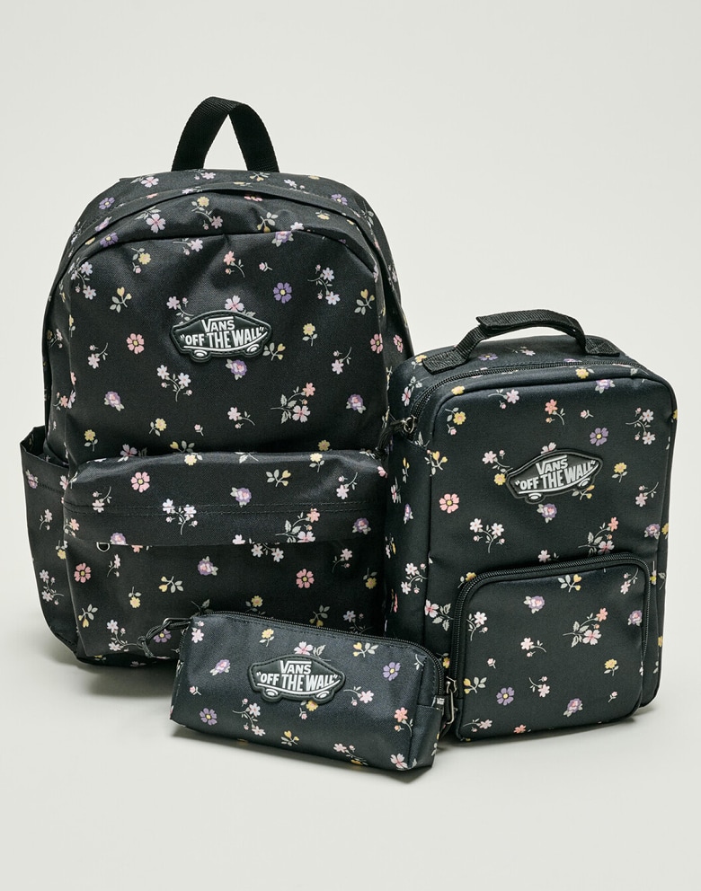 A black floral Old Skool Grom Backpack, Old Skool Lunch Bag, and Old Skool Pencil Pouch on the floor of a photography studio.