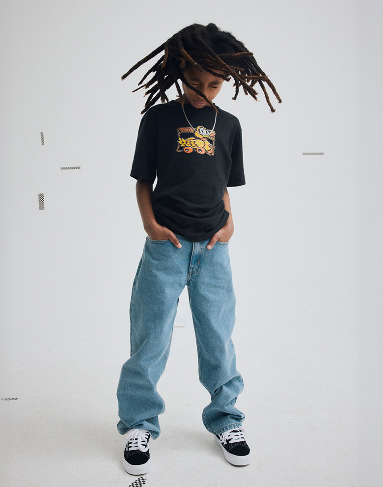 A young boy shakes his hair wearing black and white Old Skool, Kids Check-5 Loose Denim Pants, and a black Kids Rolling Fowl T-Shirt.