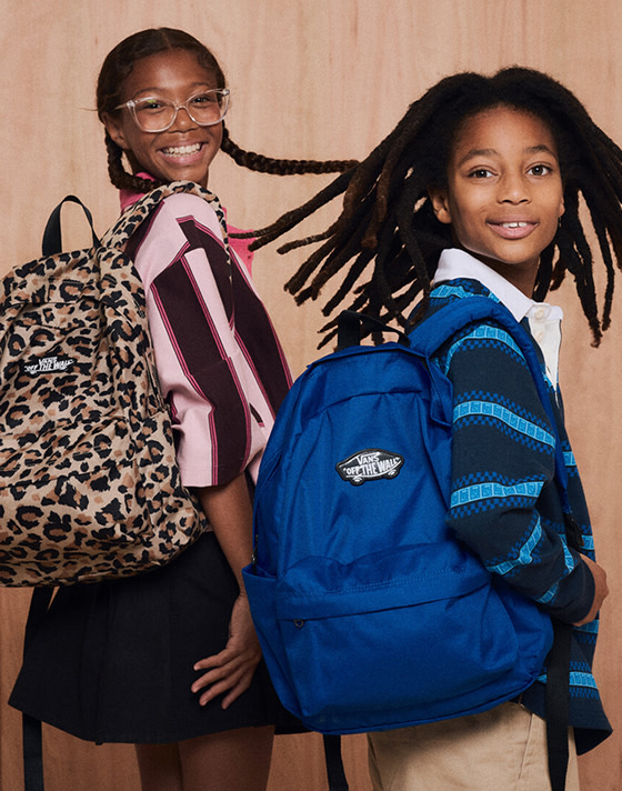 A young girl carrying a leopard print Old Skool Grom Backpack and a young boy carrying a blue Old Skool Grom Backpack.