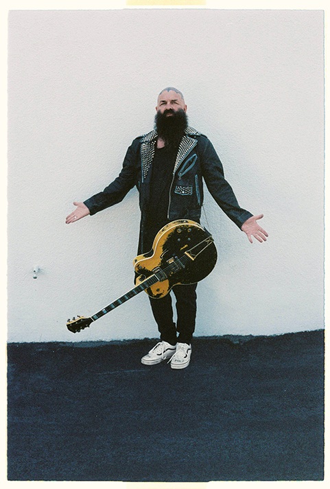 Image of a man with a guitar wearing the Vans x Travis Barker Old skool shoes.