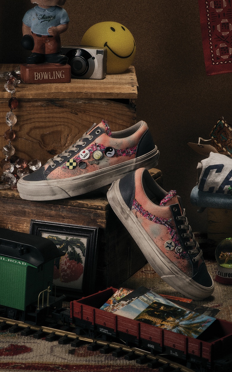 A pair of pink and black Souvenir Old Skool with Vans buttons on a dresser with a California sweater and other trinkets.
