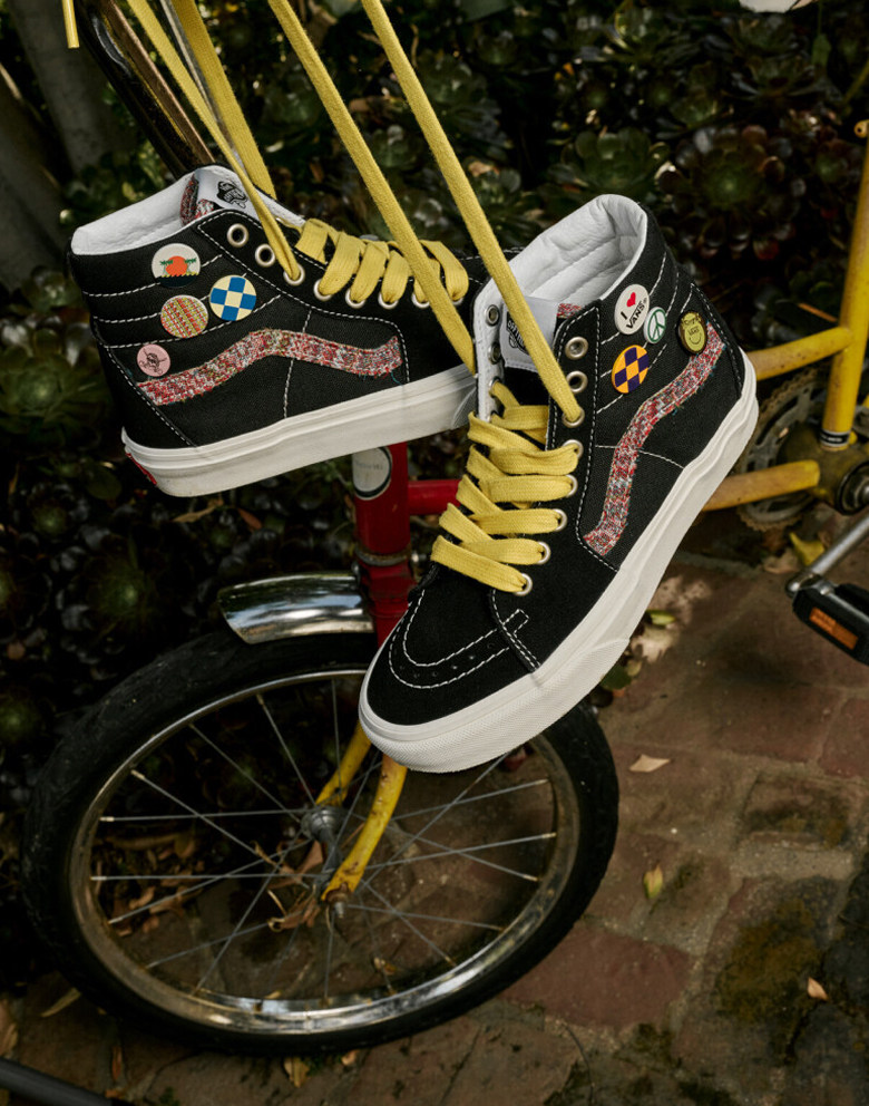 Medium shot of the Big Kids Sk8-Hi Shoe in Black / Marshmallow White with its yellow laces tied and hanging from a bike outside.