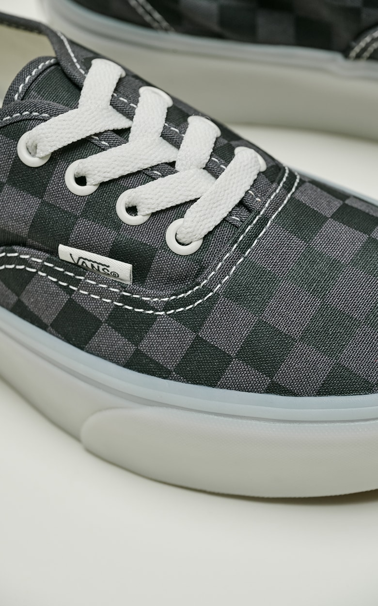 Close-up on a charcoal and black Authentic Checkerboard Platform Shoe on the floor of a photography studio.