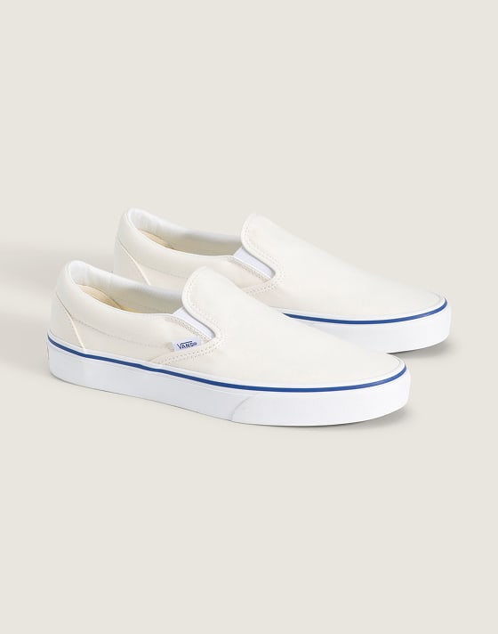 A pair of white Classic Slip-On on the floor of a photography studio.