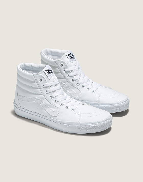 A pair of white Sk8-Hi on the floor of a photography studio.