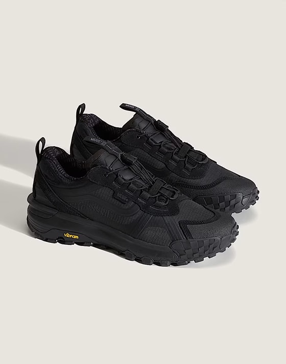 A pair of blackout Crosspath XC GORE-TEX Shoes on the floor of a photography studio.