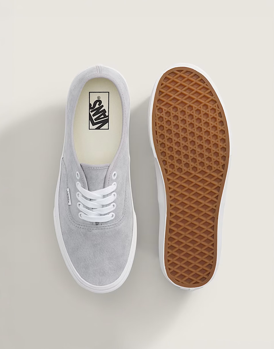 An overhead shot of a pair of gray and white Authentic on the floor of a photography studio.