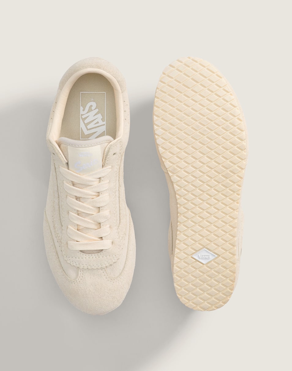 An overhead shot of a pair of sand white beige Super Lowpro shoes on the floor of a photography studio.