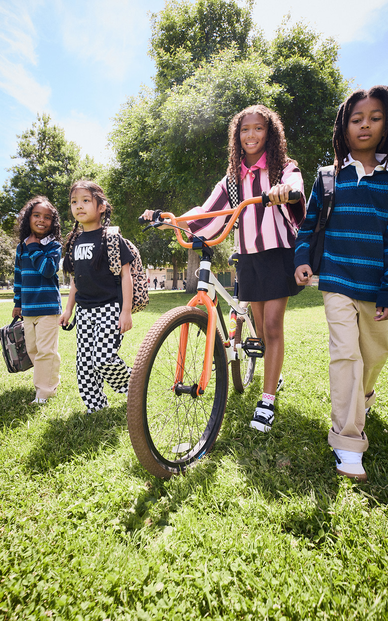 A group of kids in a field wearing Vans shoes and clothes.