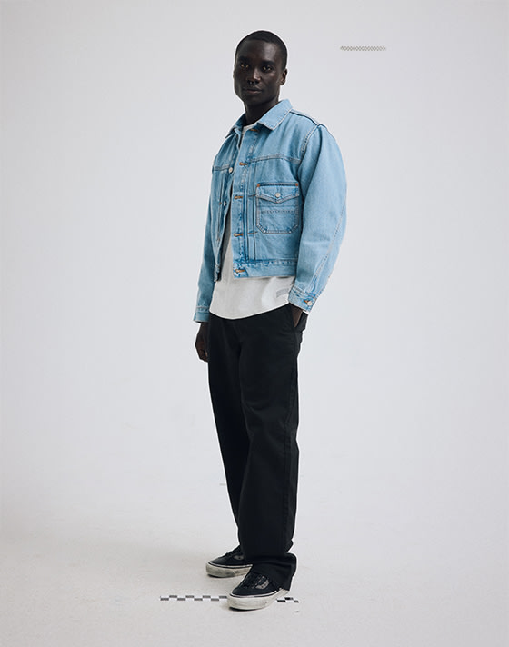 A young man poses in a photo studio wearing a light stonewash Check-5 Denim Trucker Jacket.