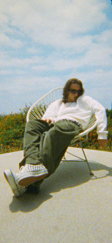 A man sitting in a chair outside wearing OTW Era 95 DST checkerboard shoes